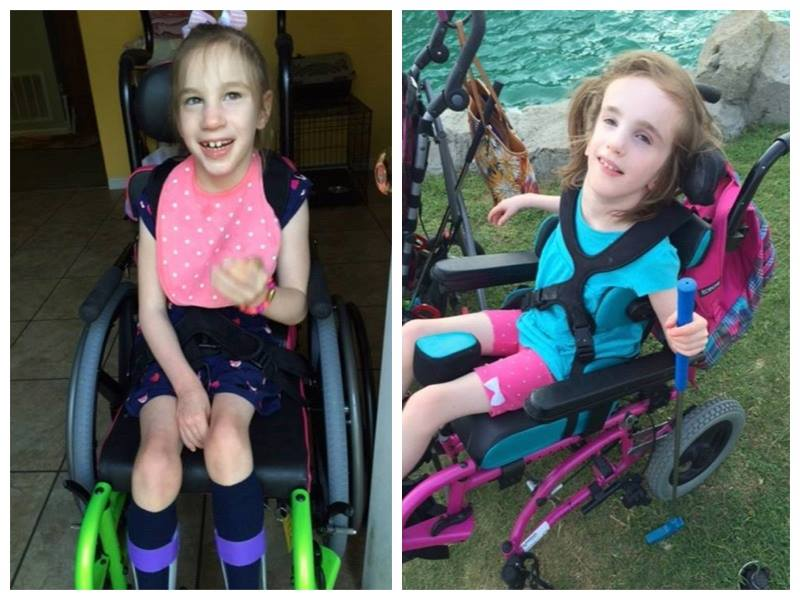 Izzy and Mikah, two young girls with light-colored hair, sit in wheelchairs. Izzy smiles indoors in a pink polka-dot shirt, while Mikah is outdoors by the water in a blue shirt and pink shorts, looking up as their story unfolds.