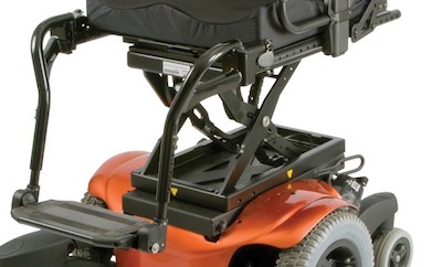 Close-up of the back and Power Seat Elevator mechanism on a modern power wheelchair with a red base, black seat, and sturdy metal frame. The seat is elevated, revealing the mechanical support underneath.