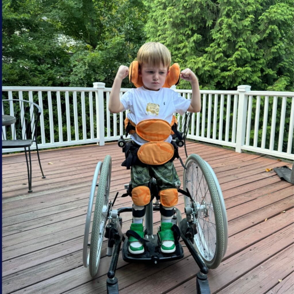 Elliot in his wheelchair flexing his arms