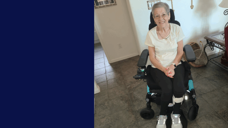 Christines Story: An older woman with short gray hair and glasses sits smiling in a wheelchair indoors, wearing a white shirt, black pants, and white sneakers. The left side of the image features a solid navy blue background.