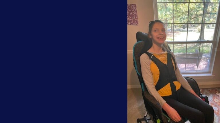 Paulinas Story: A smiling girl sits in a wheelchair near a large window with sunlight streaming in. She wears a yellow top with a gray sweater and black pants, with a harness over her shoulders. The left side of the image is solid dark blue.