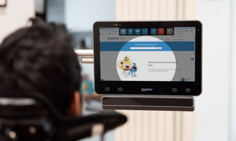 A person uses a Smartbox assistive communication device with a screen displaying the Smartbox Hub interface and interactive options powered by Smartbox Grid communication software.