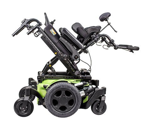 A green and black power tilt wheelchair with features allowing for tilting and reclining is shown in a partially elevated and reclined position. This complex wheelchair has large rear wheels and supports for the head, arms, and legs.
